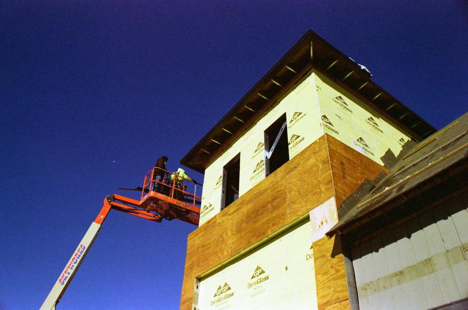 Operarios en plataforma hidráulica la lado de edificio en construcción